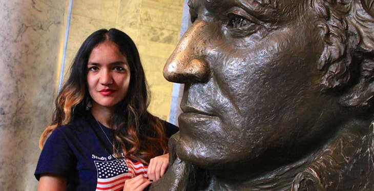 SUSI 2015 participant posing with statue of George Washington at Olympia Capitol Building.