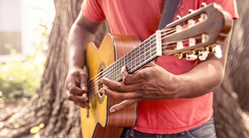 Photo of a man holding and playing a guitar.