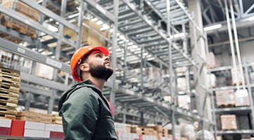 A worker in a warehouse looking up.
