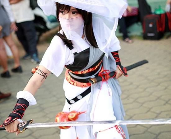 photo of a woman dressed up in a white ninja costume while holding a sword