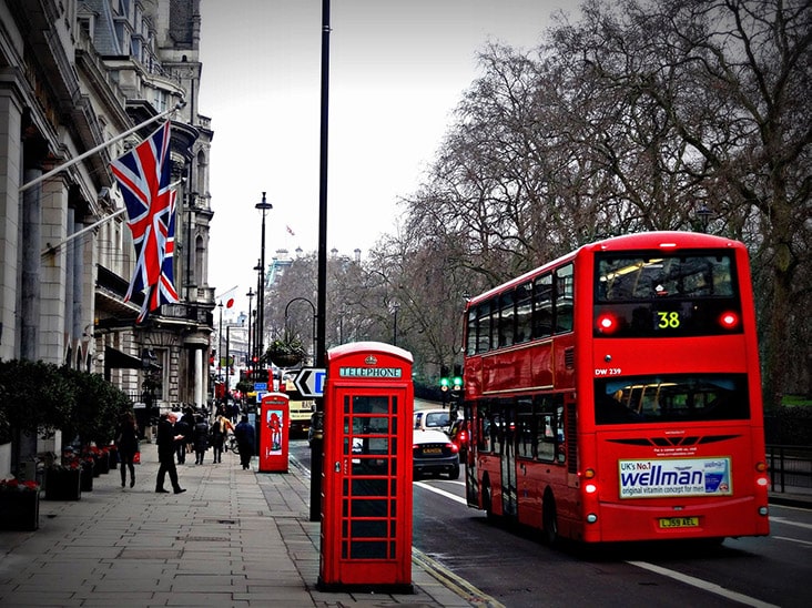A red telephone booth and double decker bus on a busy street in London.