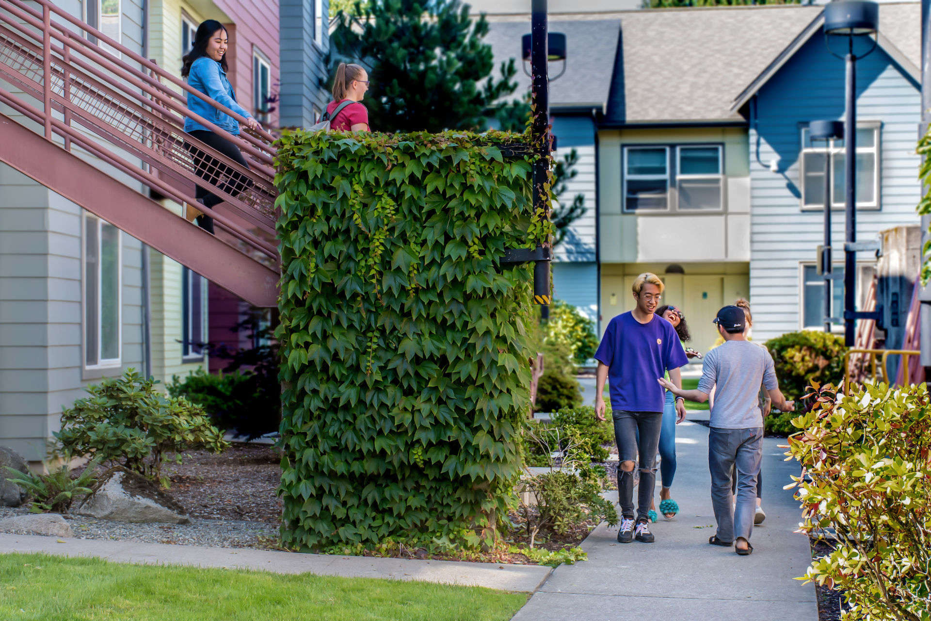 People on the stairs and walking along the sidewalk of the Campus Corner Apartments