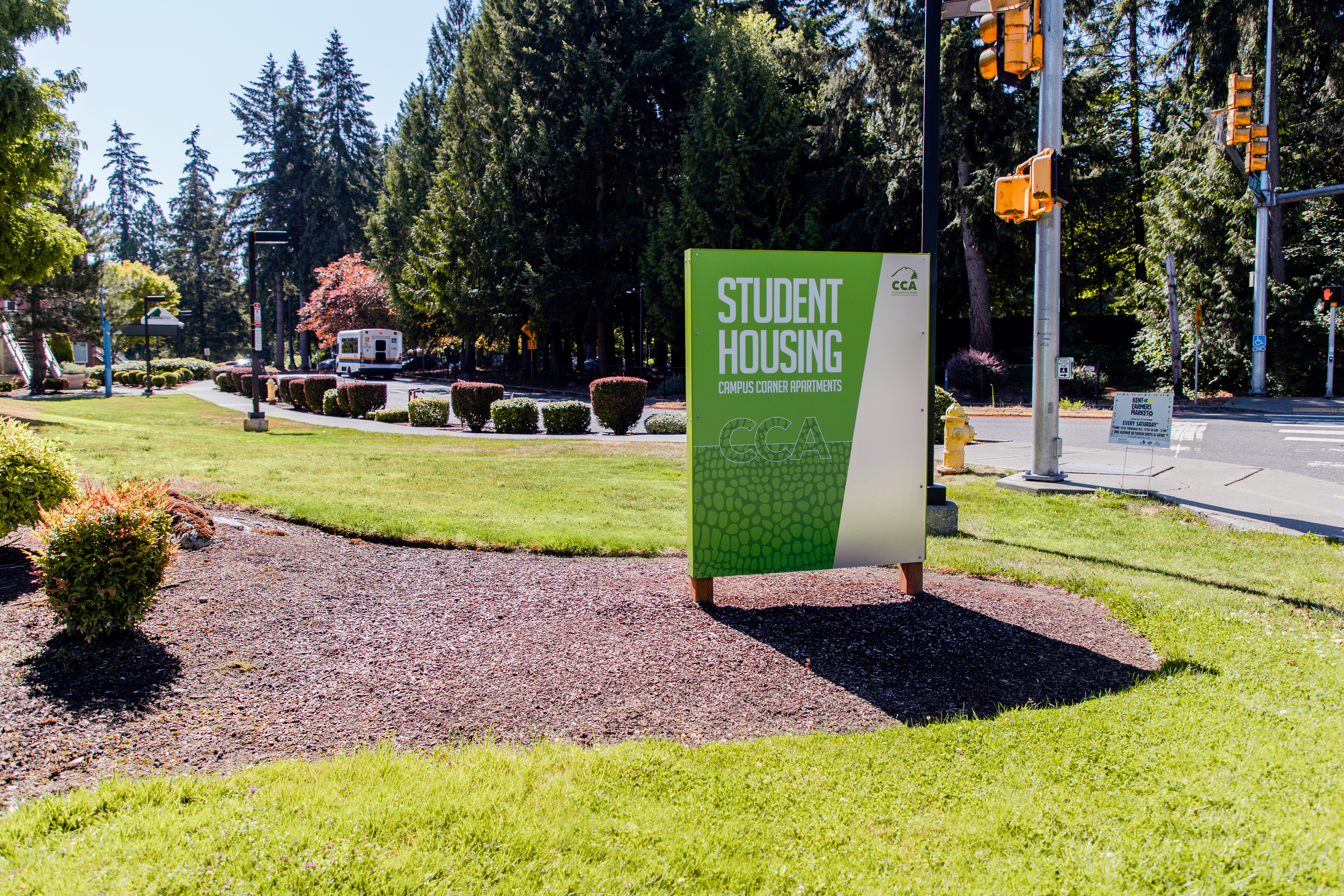 Campus Corner Apartments monument sign on brown bark surrounded by green grass