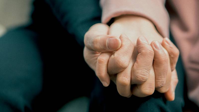 Two hands with fingers interlocked
