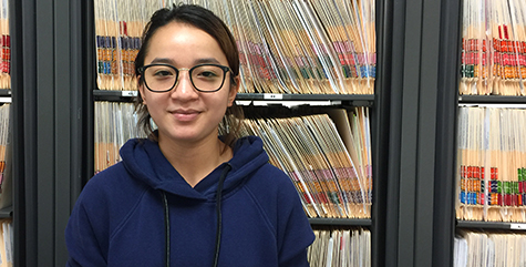 Pich Seng from Cambodia stands in front of file folders in the IP office. She participated in the Global Leadership Program