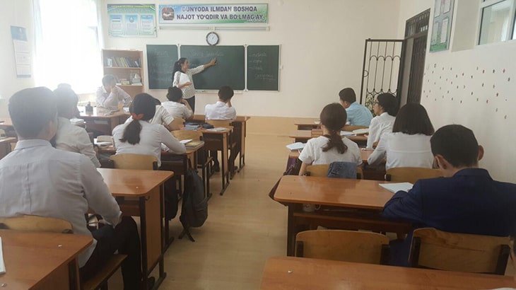 Aziza at a blackboard presenting to a classroom of students.