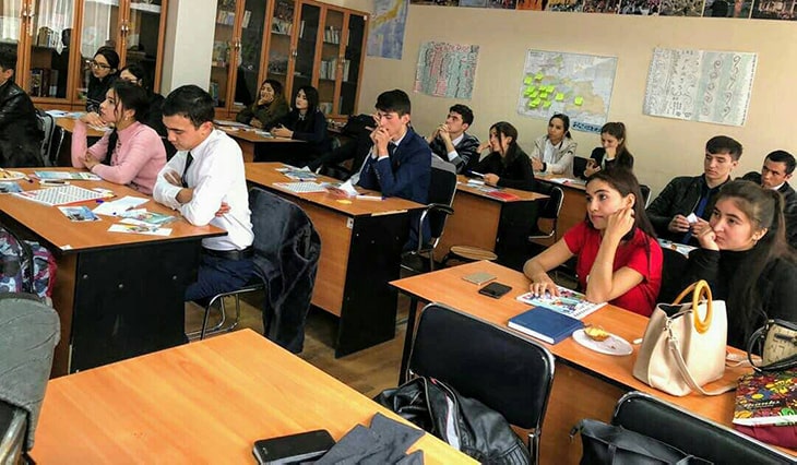 Students in a classroom listening to presentations.