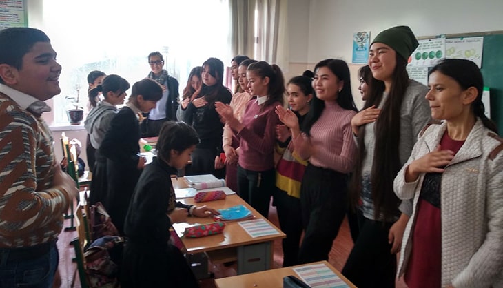 Volunteers greeting students in a classroom.