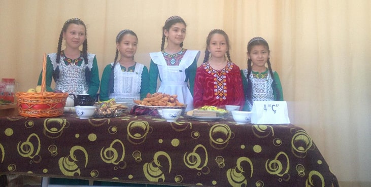 Children standing in front of cooked food dishes.