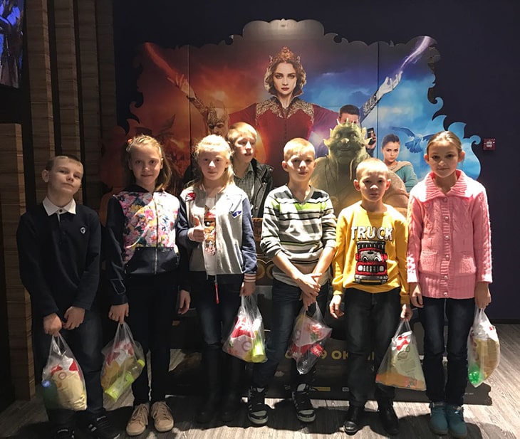 A group of children posting for a photo at a movie theater. 