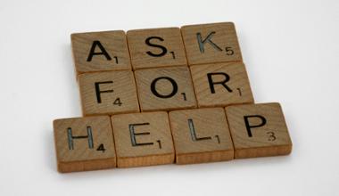 Tiles from the a board game arranged to spell out Ask For Help