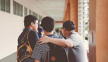 Three students standing with arms around one another