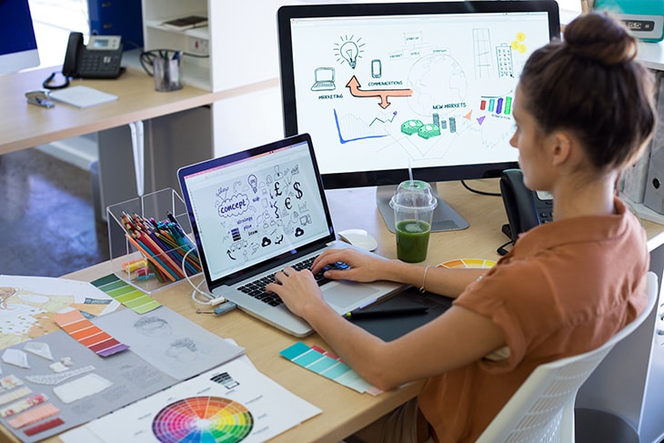 image of a woman sitting at a desk using a computer to create digital graphics and art