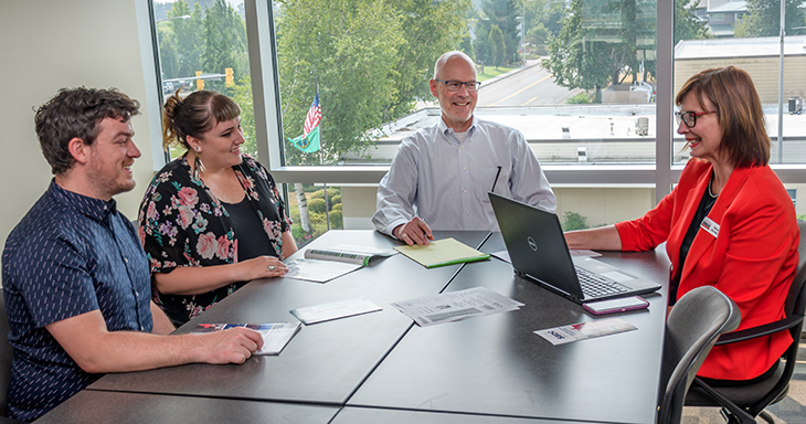 Photo of four individuals sitting at a conference table. Two of the individuals are Small Business Center advisers, and two are Small Business Center clients.